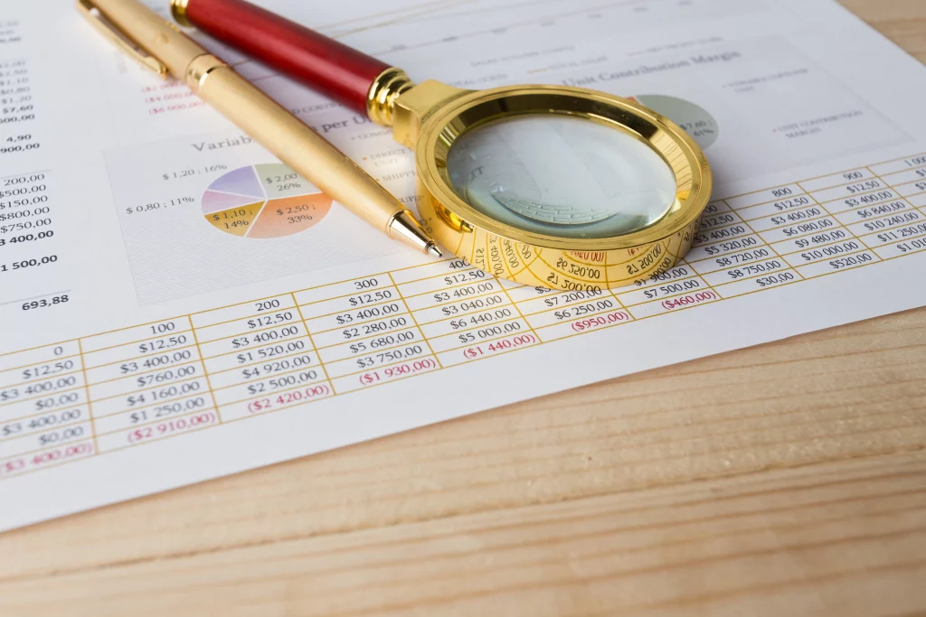 Plano de una lupa y una pluma sobre un informe simbolizando la revisión para la auditoría de cumplimiento normativo STPS