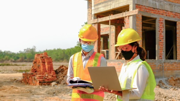 Operarios inspeccionando muros de concreto en el control de proyectos y obras de construcción.