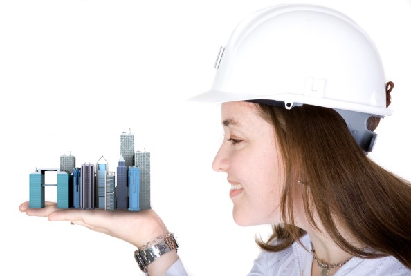 Mujer con casco sostiene una ciudad miniatura simbolizando empresas desarrolladoras de proyectos inmobiliarios.